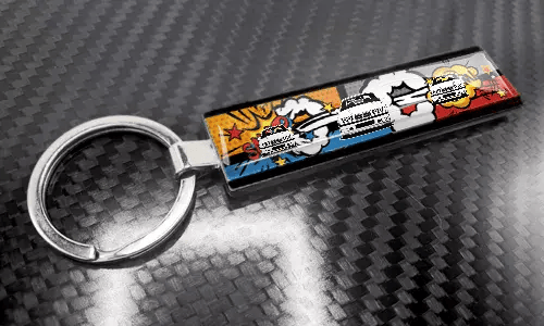 Porte-clés XL fin style bande dessinée avec un design coloré de plaque d’immatriculation sur une surface à texture carbone