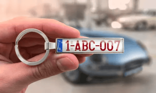 Llavero plateado de placa de matrícula muestra números personalizados mientras se sostiene en la mano