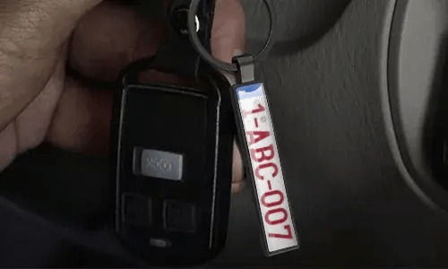 Silver license plate keychain hangs from car keys inside a vehicle