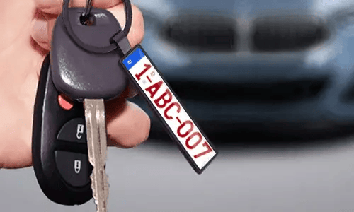 Black license plate keychain hangs from car keys in everyday use