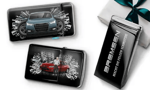 Three sleek black wallets with images of cars and gears, placed near a gift box. 