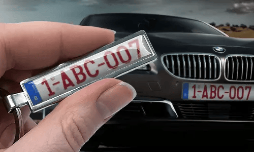 Sleutelhanger in stripstijl met kentekenplaat, vastgehouden in een hand voor een auto met bijpassende platen